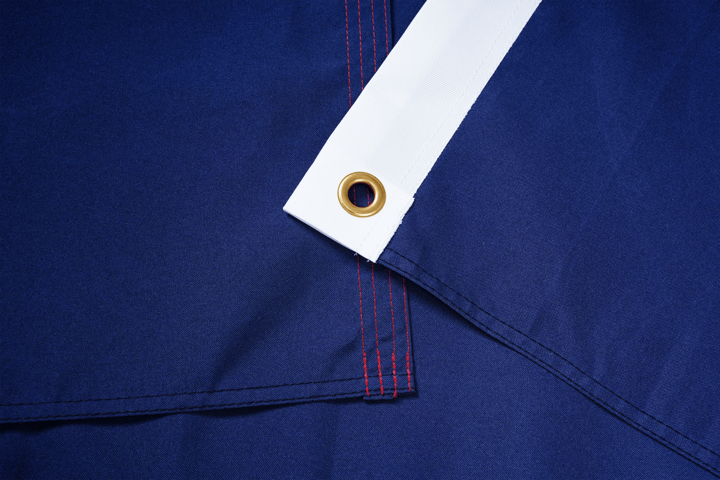 Close-up of blue fabric with a white trim and gold eyelet.