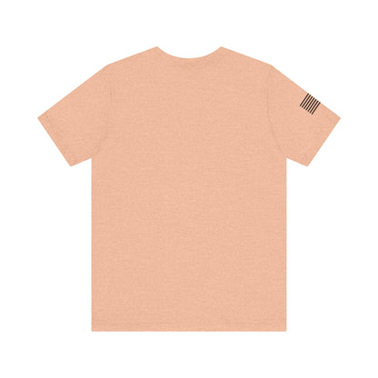 Beige t-shirt with a small flag patch on the sleeve against a white background