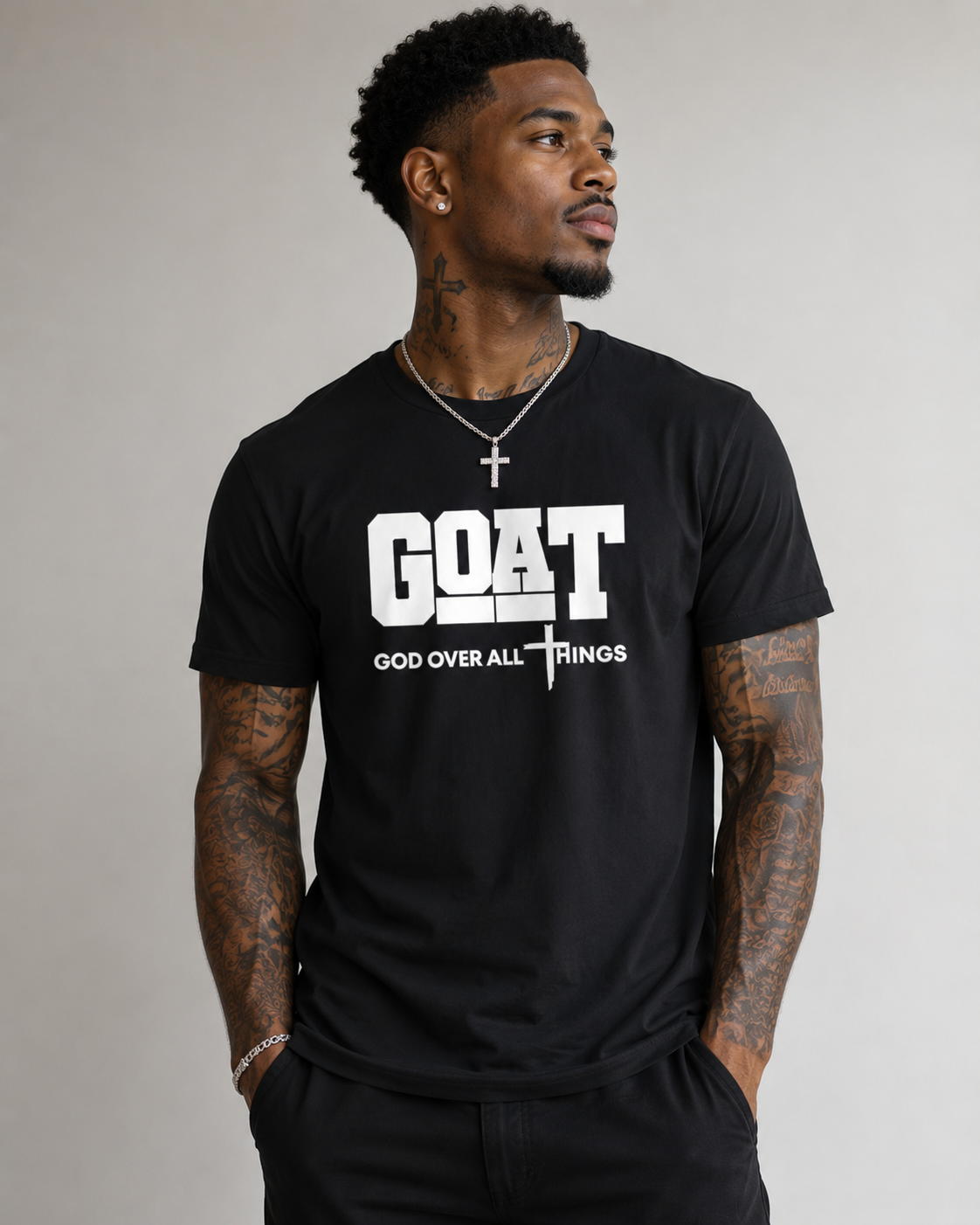 Man wearing a black t-shirt with 'GOAT God Over All Things' text on a plain background