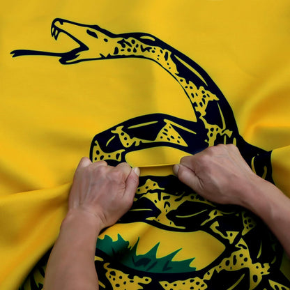 Yellow flag with a black snake design held by hands