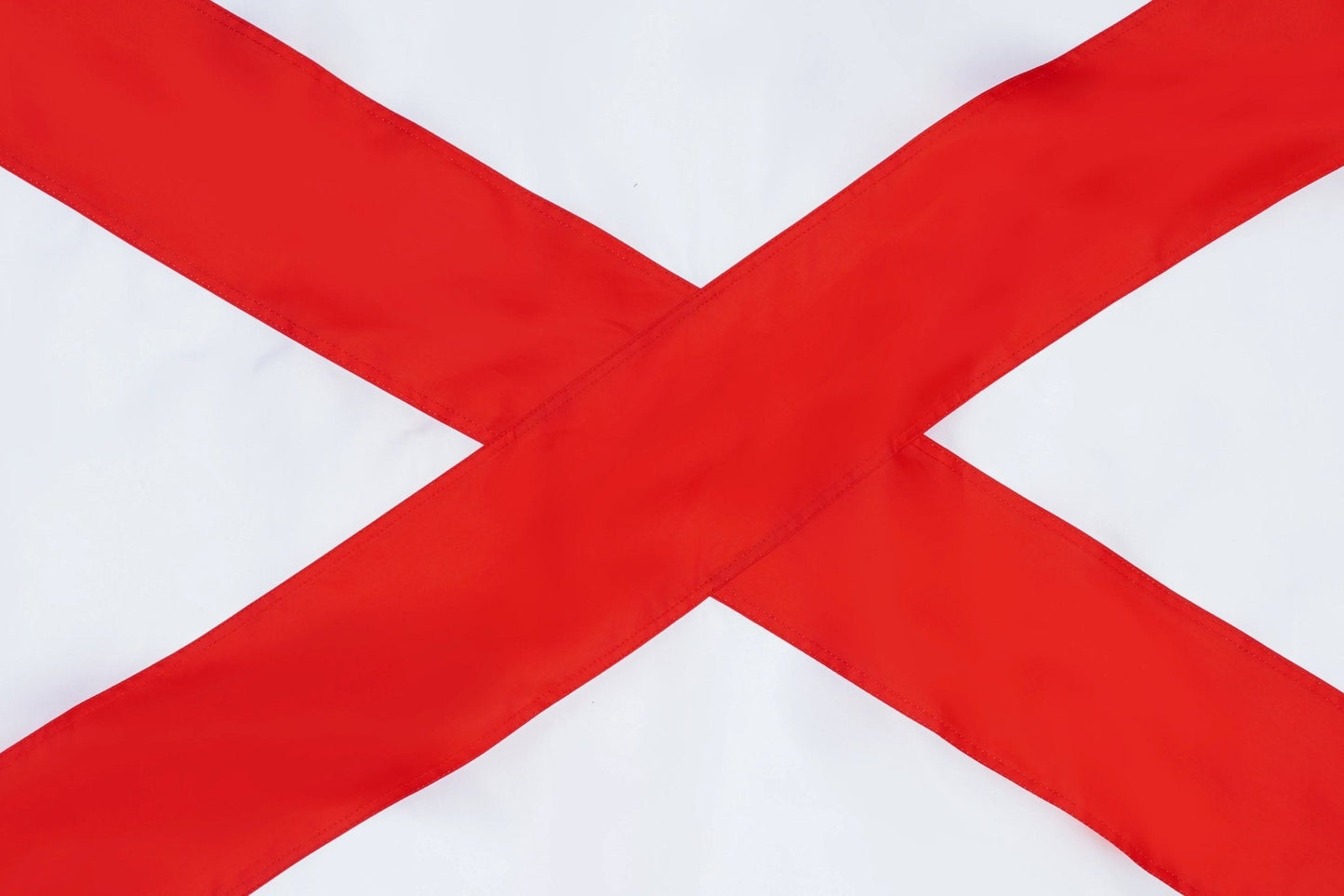 A close-up of a white flag with a bold red diagonal cross, filling the frame.