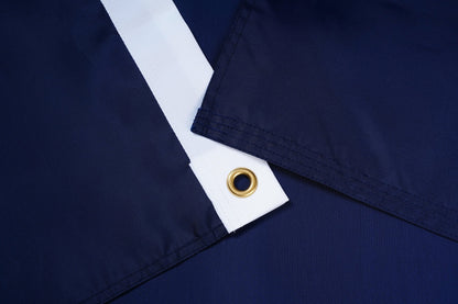 Close-up of navy blue fabric with a white stripe and gold grommet.