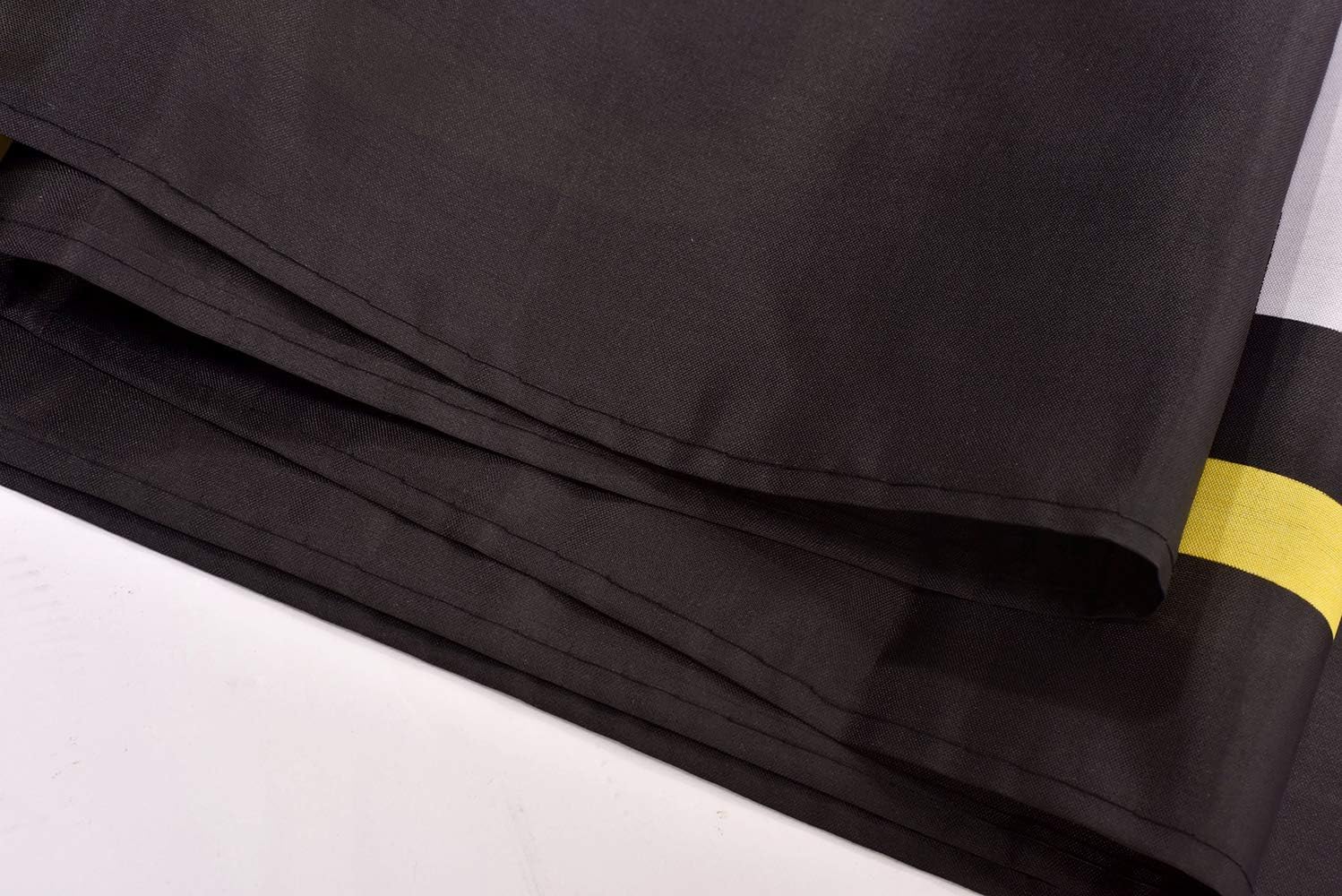 Close-up of black fabric with a yellow stripe on a white background