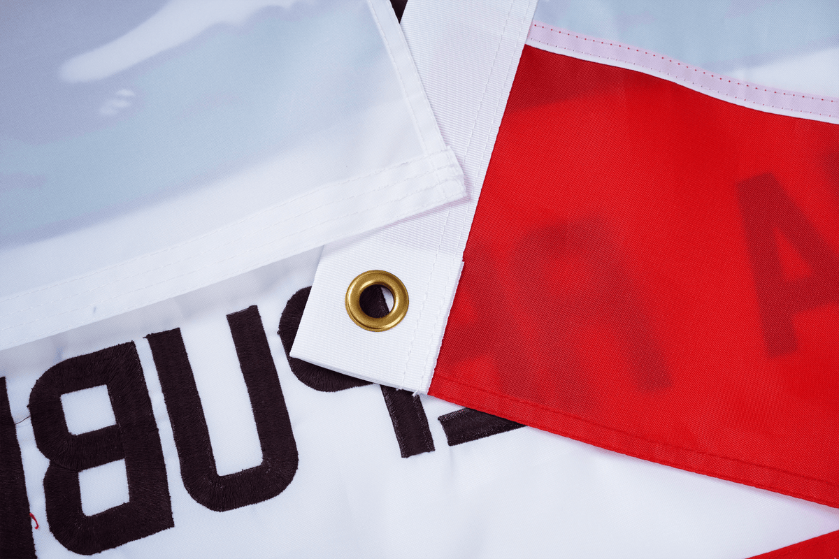 Close-up of fabric with text and a gold button, featuring a brand logo.
