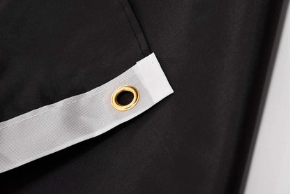 Close-up of a black fabric with a gold eyelet on a white strip.